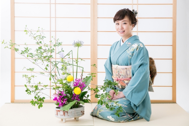 着物姿の女性が正座して花を生けている