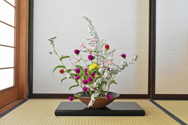 和室の床の間に置かれた水盤に、色とりどりの草花が生けられている