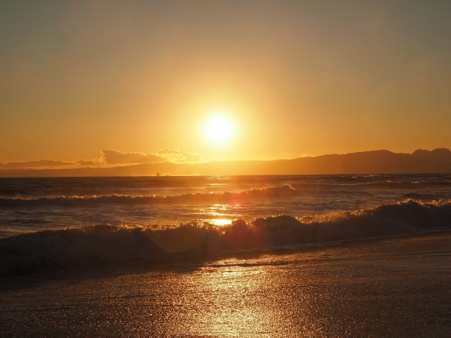 夕日が沈む辻堂海岸の砂浜と打ち寄せる波