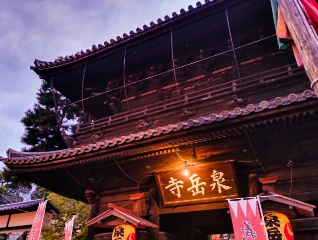 提灯の明かりに照らされた夕暮れの泉岳寺の山門
