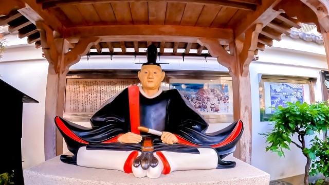 屋根の下に座る、烏帽子に装束姿の吉良上野介の像