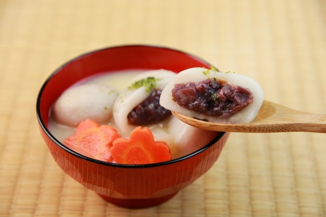白味噌のお雑煮から、あんこの入った丸餅をスプーンですくったところ