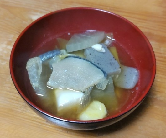 赤い内側の椀に盛られたくじら汁。くじらの皮やこんにゃく、野菜が入っている